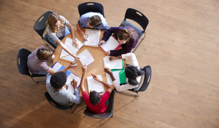Overhead Shot Of High School Pupils In Group Study Around Tables