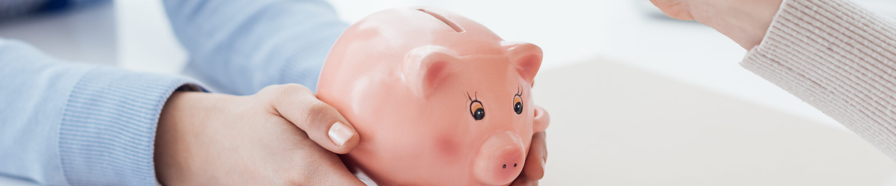 Financial advisor holding a piggy bank and customer inserting a coin: investments, savings plan and retirement fund concept