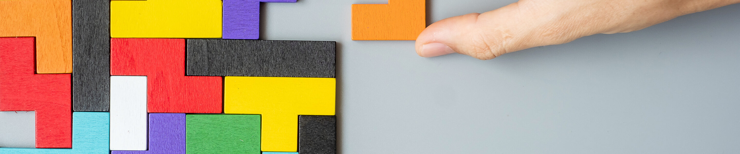 hand connecting geometric shape block with colorful wood puzzle pieces. logical thinking, business logic, Conundrum, decision, solutions, rational, mission, success, goals and strategy concepts