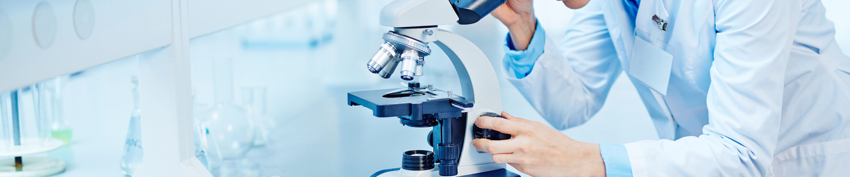 Young scientist studying new substance or virus in microscope