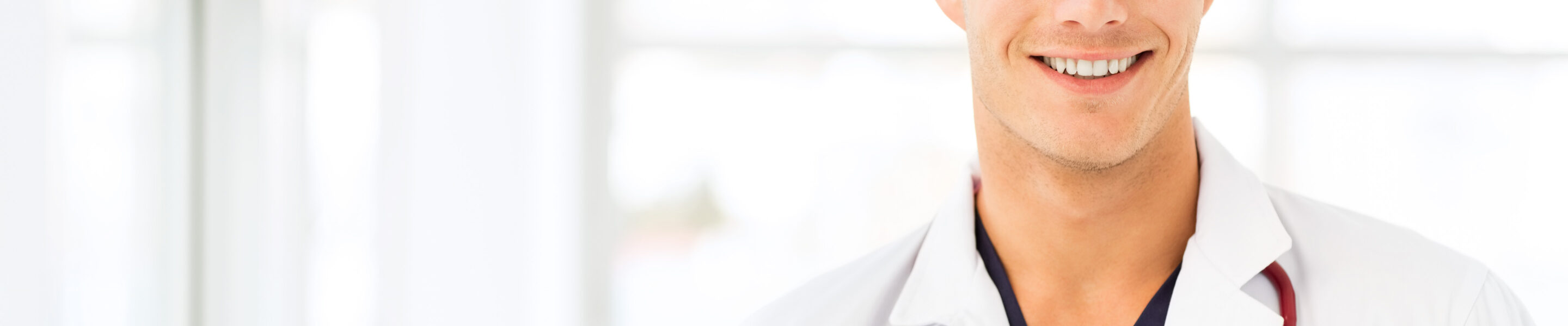 Portrait of handsome young male doctor smiling in hospital. Horizontal shot.