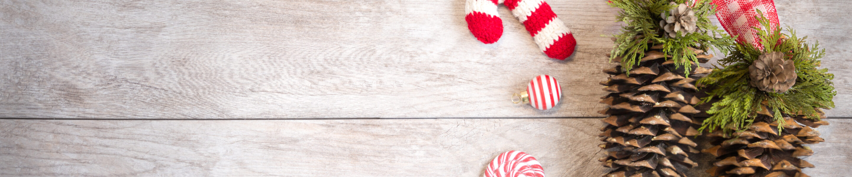 Festive Winter holiday wood background with ornaments, knitted ornament, candy and pine-cones.