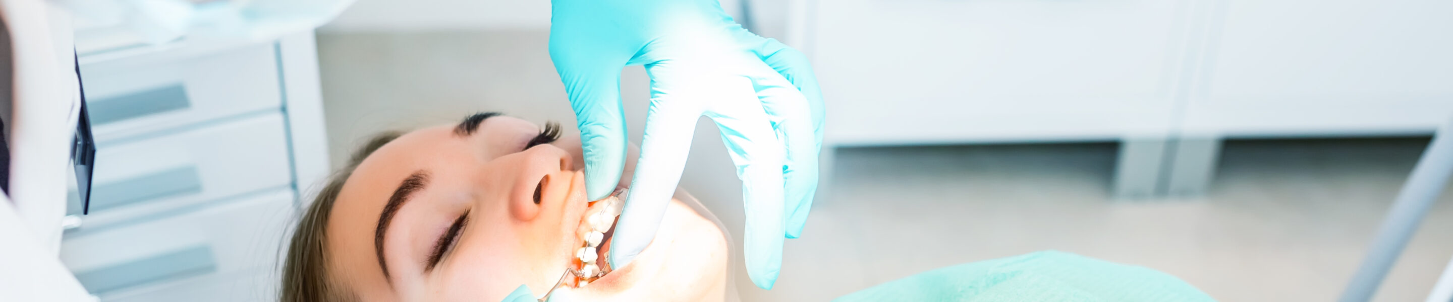 Female dentist checking up patient teeth with metal braces at dental clinic office. Medicine, dentistry and health care concept. Dental equipment