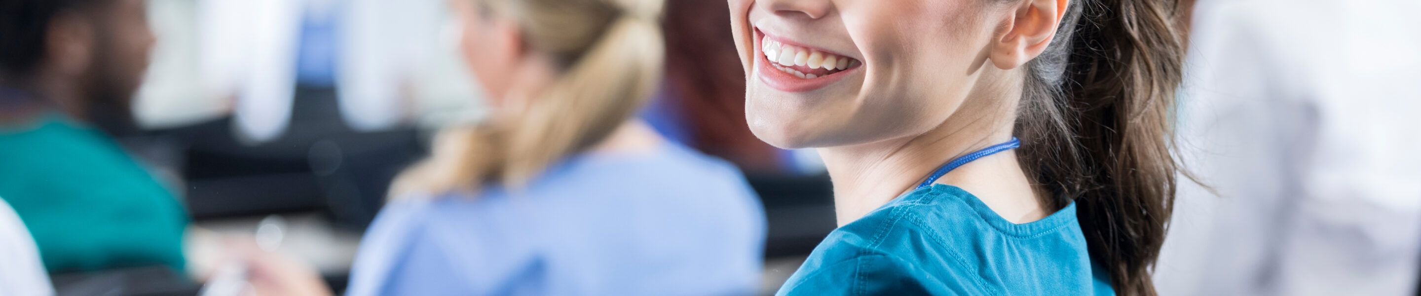 Beautiful young Hispanic female medical student smiles over her shoulder while attending class.