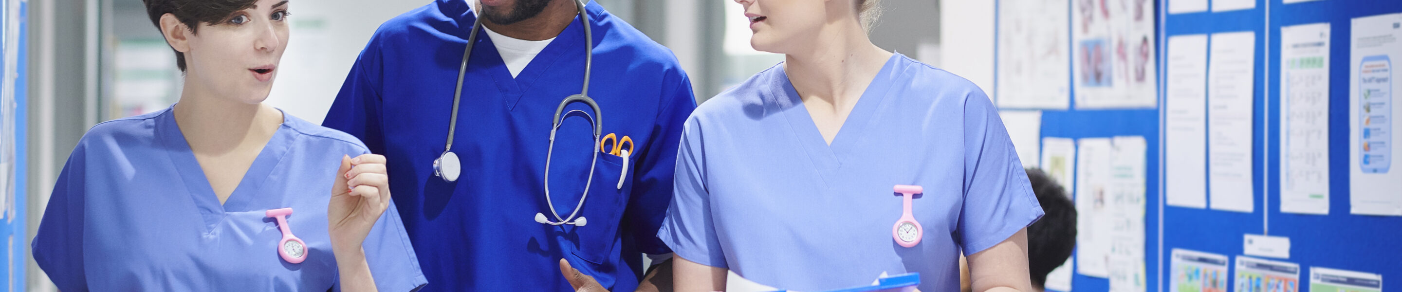 a medical consultant with two nurses walk along a hospital corridor