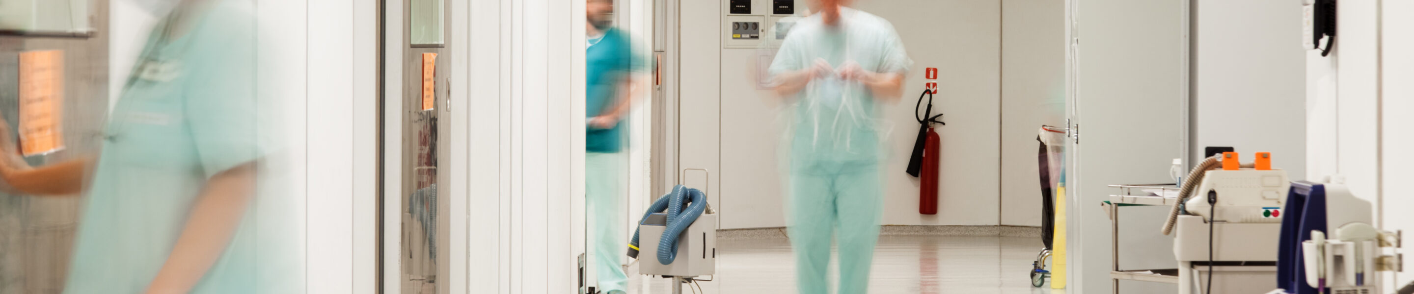 A sterile corridor to operating rooms in modern hospital with motion blurred figures of doctors and nurses.