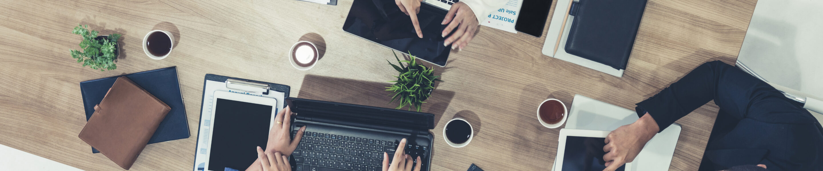 Top view of businessman executive in group meeting with other businessmen and businesswomen in modern office with laptop computer, coffee and document on table. People corporate business team concept.