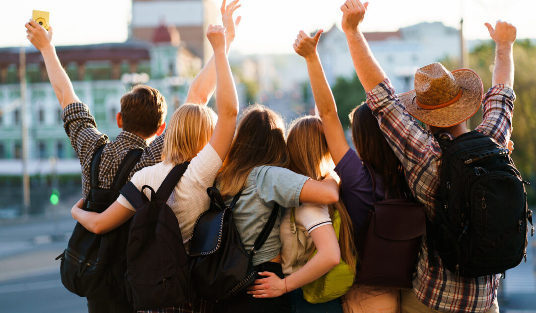 Traveling, sightseeing, group travel, city tour, student exchange program, vacation, holiday, togetherness and friendship. People with backpacks rising hands, joy and positivity