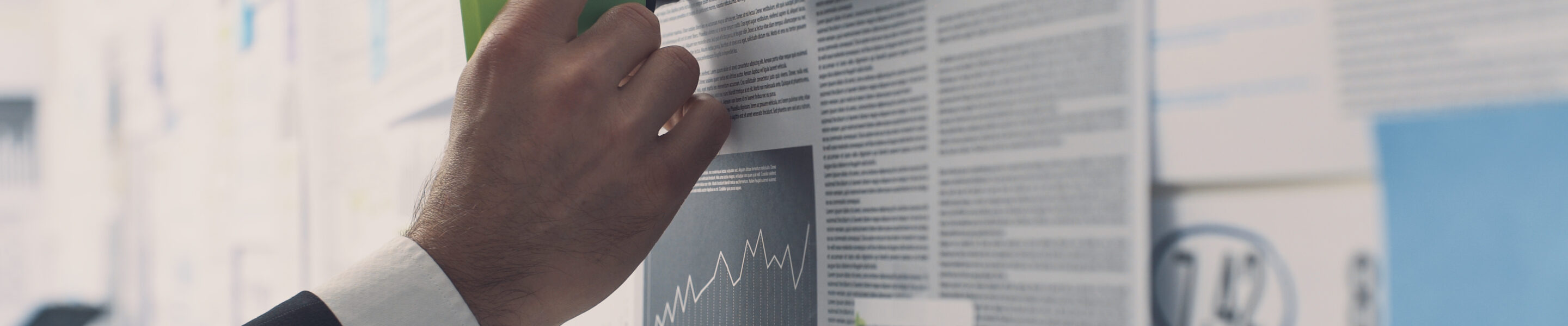 Businessman analyzing a wall with many financial charts and reports, he is underlining text with a marker