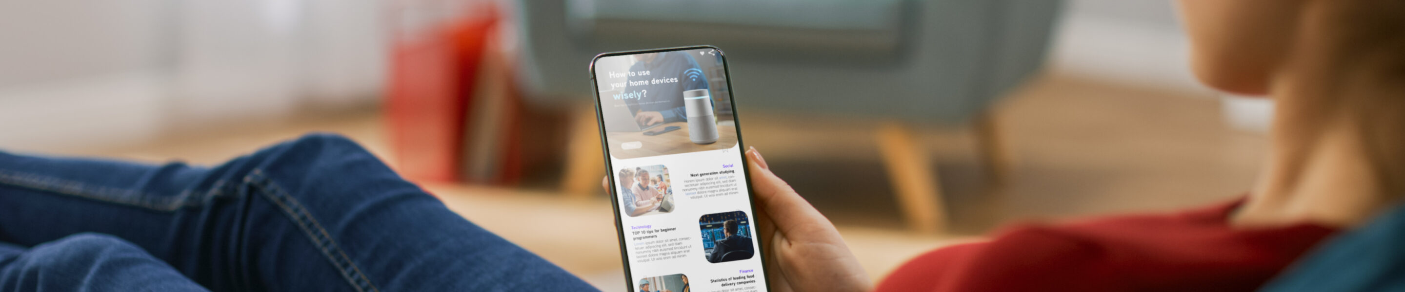 Young Woman at Home Uses Smartphone for Scrolling and Reading News about Technological Breakthroughs. She's Sitting On a Couch in Her Cozy Living Room. Over the Shoulder Shot