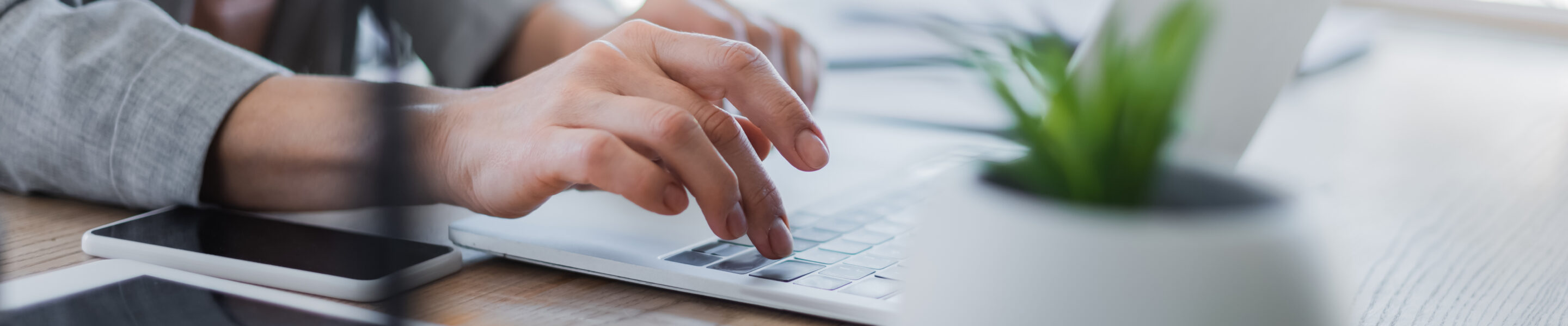 Cropped view of businesswoman using laptop near gadgets on table