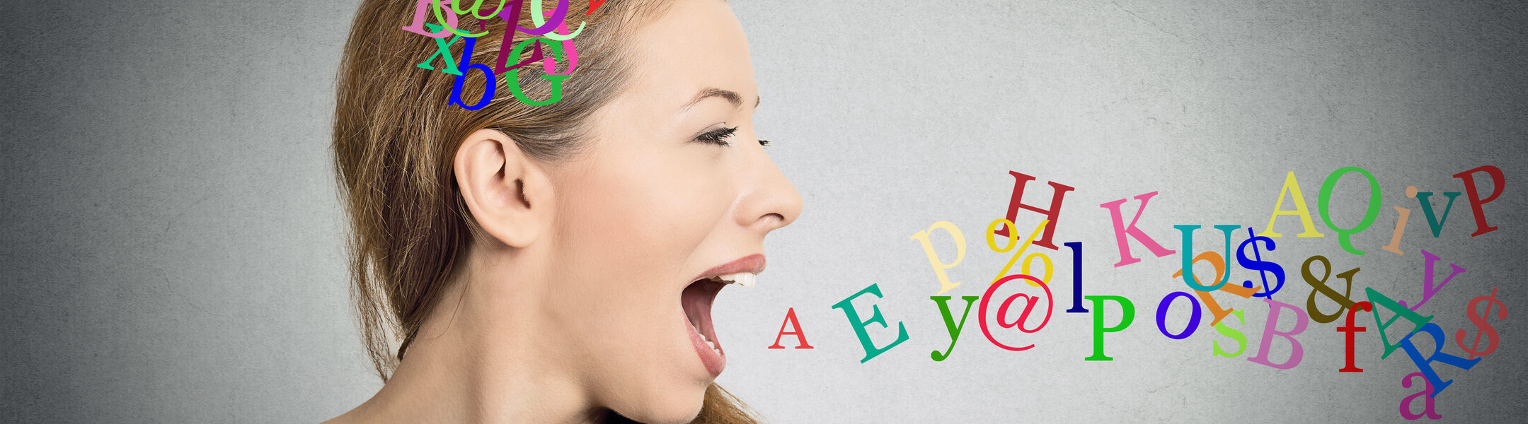 Side view portrait woman talking with alphabet letters in her head and coming out of her open mouth isolated grey wall background. Human face expressions, emotions. Communication, intelligence concept