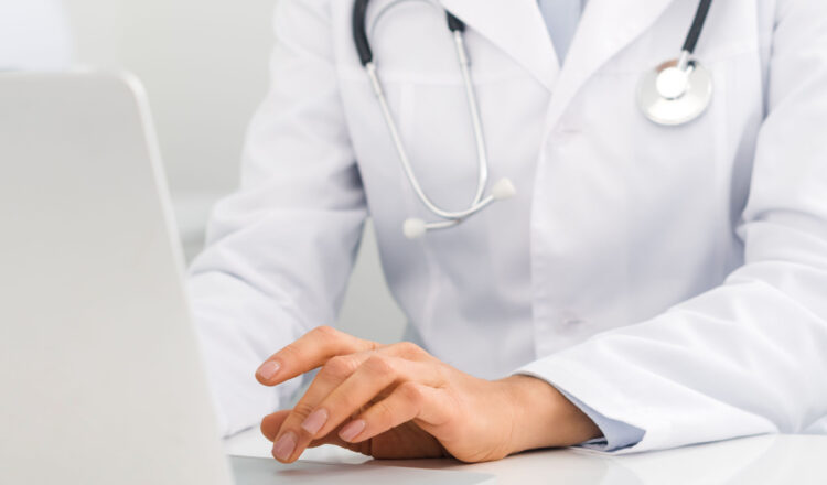 panoramic shot of professional female doctor working on laptop in clinic